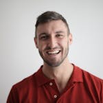 A cheerful man smiling broadly against a plain white background.