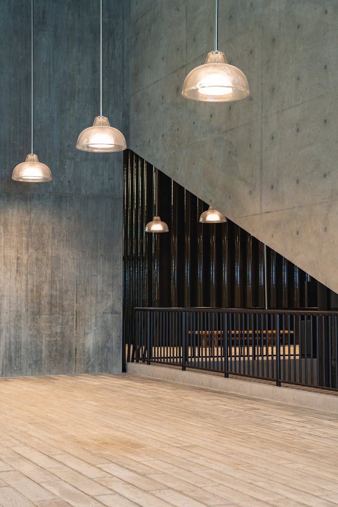 A sleek industrial space featuring concrete walls and modern pendant lighting.